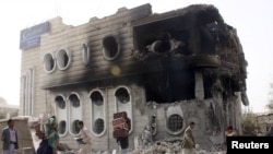 FILE - People salvage belongings from a government bank that was hit during an air strike in Yemen's northwestern city of Saada April 16, 2015. 