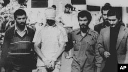 FILE - One of 60 U.S. hostages, blindfolded and with his hands bound, is being displayed to the crowd outside the U.S. Embassy in Tehran by Iranian hostage takers, Nov. 9, 1979. 