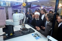 FILE - President Hassan Rouhani listens to explanations of nuclear achievements in Tehran, April 9, 2018. Iran has broken the limit set on its stockpile of low-enriched uranium by the 2015 nuclear deal, and will raise its enrichment of uranium.