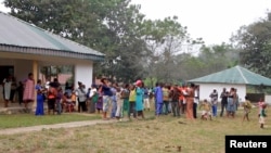 FILE - Cameroonian refugees stand outside a center in Agbokim Waterfalls village, which borders on Cameroon, in Nigeria, Dec. 9, 2017.