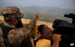 FILE - A Pakistan army officer points out the Indian forward area posts to journalists at Bagsar post on the Line of Control that divides Kashmir between Pakistan and India, on October 1, 2016.