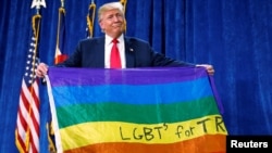 Le président, alors candidat, tient un drapeau LGBT à Greenley, Colorado, le 30 octobre 2016.