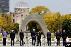 U.S. Secretary of State John Kerry, center left, puts his arm around Japan's Foreign Minister Fumio Kishida, center right, after they and fellow G7 foreign ministers laid wreaths at the cenotaph at Hiroshima Peace Memorial Park in Hiroshima, western Japan