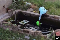 FILE - A man fetches water from a concrete tank in an upcoming residential neighborhood in Bangalore, India, May 3, 2018.