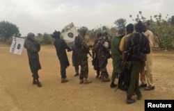 Boko Haram militants (in camouflage) embrace and shake hands with Boko Haram prisoners, released in exchange for a group of 82 Chibok girls, who were held captive for three years by Islamist militants, near Kumshe, Nigeria, May 6, 2017.