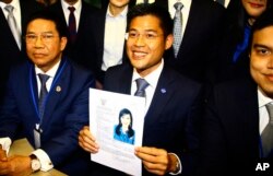 Leader of Thai Raksa Chart party Preechapol Pongpanich, center, holds a picture of Princess Ubolratana at election commission of Thailand in Bangkok, Feb. 8, 2019.