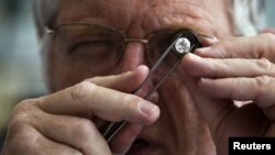 A British diamond dealer inspects a raw diamond on the trading floor of Israel's diamond exchange in Ramat Gan near Tel Aviv, October 30, 2012.