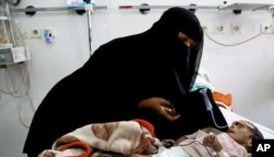 FILE - In this March 22, 2016 photo, Udai Faisal, who is suffering acute malnutrition is fed by his mother Intissar Hezzam at al-Sabeen Hospital in Sanaa, Yemen.