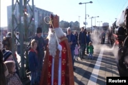 FILE - Children in Munich, Germany, get a surprise visit from St. Nicholas before they board an old-fashioned steam train for a special Christmas ride with him.