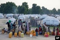 FILE- People displaced by Islamist extremists fetch water at the Muna camp in Maiduguri, Nigeria.