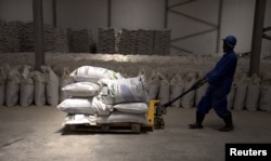 A worker pulls a trolley loaded with sacks of fishmeal produced by the Omaurci SA company in Nouadhibou, Mauritania, April 14, 2018.