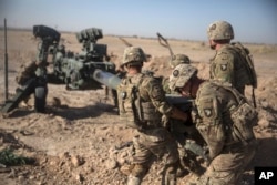 FILE - Photo provided by Operation Resolute Support, U.S. Soldiers with Task Force Iron maneuver an M-777 howitzer, so it can be towed into position at Bost Airfield, Afghanistan, June 10, 2017.