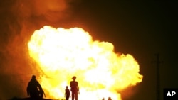 Egyptian Bedouins watch as smoke and flames rise into the air after masked gunmen blew up a terminal of the Egyptian natural gas pipeline to Israel and Jordan in el-Arish, in the northern part of Egypt's Sinai Peninsula, July 12, 2011