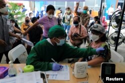 Petugas medis melakukan pemeriksaan kesehatan terhadap seorang wanita yang akan menerima dosis vaksin booster di Jakarta, 12 Januari 2022. (Foto: REUTERS/Willy Kurniawan)
