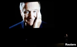 Billy Crystal takes the stage to pay tribute to the late Robin Williams, shown on a large screen, during the 66th Primetime Emmy Awards in Los Angeles, Aug. 25, 2014.
