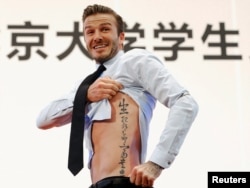 Football star David Beckham displays a tattoo, as requested by students at Peking University, during a visit to Beijing, March 24, 2013. Its translation: "Life and death are determined by fate, rank and riches decreed by Heaven."