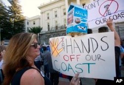 Bethany Webb, of Huntington Beach, joins other protesters at a rally against oil drilling off the California coast at the state Capitol before marching to a hearing by the U.S. Bureau of Ocean Energy Management, Feb. 8, 2018, in Sacramento, Calif.