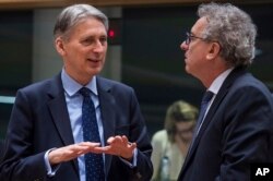 FILE - Britain's Chancellor of the Exchequer Philip Hammond, left, talks with Luxembourg's Finance Minister Pierre Gramegna during a round table meeting of EU finance ministers at the EU Council building in Brussels on Jan. 27, 2017.