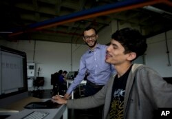 FILE - In this March 7, 2018, photo, Gabriel Jimenez, the chief strategist of Venezuela’s government-backed cryptocurrency, standing, jokes with one of his employees at the office of his company "The Social Us" in Caracas, Venezuela.