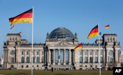 FILE - In this March 5, 2013 file photo German flags fly in front of the Reichstag building, host of the German Federal Parliament Bundestag, in Berlin, Germany.