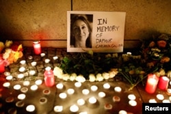 FILE - Candles burn to commemorate the killed investigative journalist Daphne Caruana Galizia in Berlin, Germany, Oct. 20, 2017.