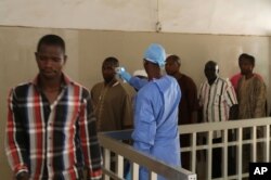 A health worker takes the temperature of people to see if they might be infected by the Ebola virus inside the Ignace Deen government hospital in Conakry, Guinea, March 18, 2016.