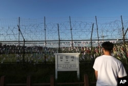 A man walks by the wire fences adorned with national flags near an information sign showing the distance to North Korea's Kaesong city and South Korea's capital, Seoul, at the Imjingak Pavilion in Paju, South Korea, Sept. 15, 2017. North Korea conducted its longest-ever test flight of a ballistic missile Friday, sending an intermediate-range weapon hurtling over U.S. ally Japan into the northern Pacific Ocean.