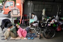Seorang pasien COVID-19 beristirahat di luar tenda darurat yang didirikan di luar rumah sakit di tengah lonjakan kasus COVID-19 di Bekasi, 25 Juni 2021. (Foto: Willy Kurniawan/Reuters)