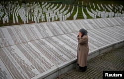 FILE - Bida Smajlovic prays near the memorial plaque with names of those killed in the Srebrenica massacre, in Potocari near Srebrenica, Bosnia and Herzegovina, March 24, 2016.