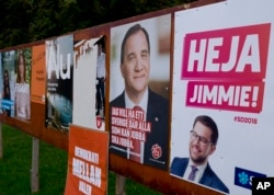 This photo shows an election poster or Jimmie Akesson, right, leader of the far-right Sweden Democrats, and Social Democratic Prime Minister Stefan Lofven, second from right. in Flen, Sweden, Aug. 30, 2018. Sweden's 7.3 million voters go to polls on Sept. 9 to elect a new parliament and government.