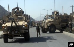 FILE - A U.S. soldier directs his colleagues at the site of a bomb attack that targeted several armored vehicles belonging to forces attached to the NATO Resolute Support Mission, in downtown of Kabul, Oct. 11, 2015.