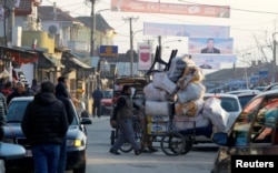 A vendor pushes a wheelbarrow under electoral posters in Suto Orizari, a district with Europe's largest Roma communities, Macedonia, Dec. 7, 2016.
