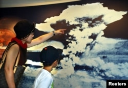 Seorang ibu dan putranya melihat gambar awan jamur bom atom di Museum Memorial Perdamaian di Hiroshima.