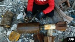FILE - A Syrian man shows remnants of rockets reportedly fired at the rebel-held besieged town of Douma in the eastern Ghouta region on the outskirts of the capital, Damascus, Jan. 22, 2018.