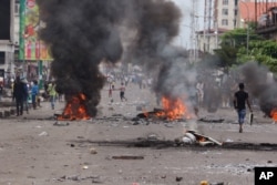 People walk near burning debris during election protests in Kinshasa, Democratic Republic of Congo, Sept. 19, 2016.
