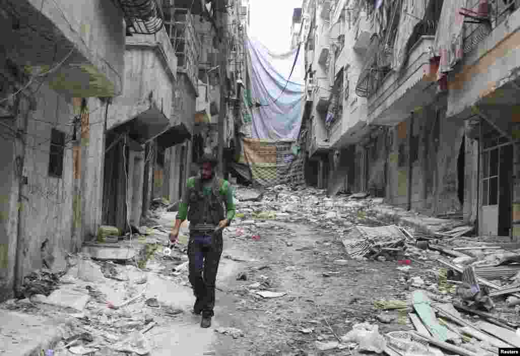 A Free Syrian Army fighter carries handcuffs as he walks along the rubble of damaged buildings in Aleppo's Salaheddine neighborhood, Nov. 7, 2013.