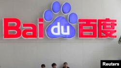 FILE - People sit in front of the company logo of Baidu at its headquarters in Beijing, China, Dec. 17, 2014. 