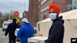  In this April 1, 2020 photo provided by Paramjyoti Kaur Singh, Singh family members Baani, Shalinder, Arjun and Jasveen Kaur pose for a photo before delivering pizzas to health care workers in Detroit. 