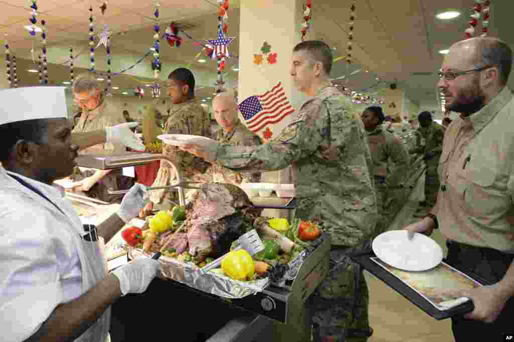 A dining facility worker, left, serves soldiers and civilians for their Thanksgiving meal at the U.S.-led coalition base in Kabul, Afghanistan, November 22, 2012.