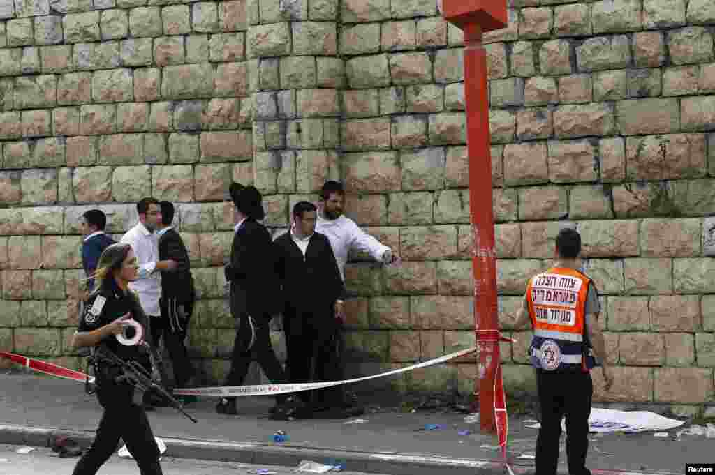 A motorist rammed into pedestrians on a crowded Jerusalem street and then got out of his vehicle to attack people with a metal bar on Wednesday according to police, who shot him. Here passers-by stand at the scene of the attack, Nov. 5, 2014.