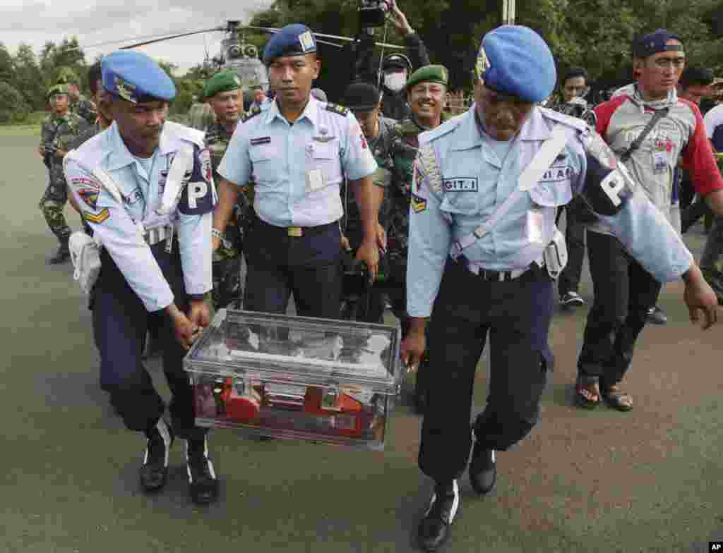 Para anggota TNI AU membawa kotak hitam data penerbangan pesawat AirAsia Flight QZ8501 di bandara Pangkalan Bun, Kalimantan tengah.