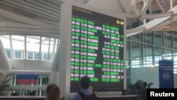 Turis asing terlihat di dekat papan informasi penerbangan di Bandara Internasional Ngurah Rai Bali, Kuta, Bali. (Foto: REUTERS/Kanupriya Kapoor)