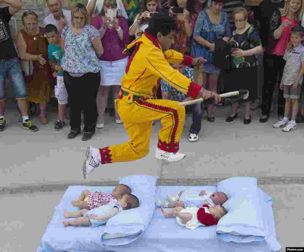 A man dressed in a red and yellow costume representing the devil, known as El Colacho, jumps over babies placed on a mattress during traditional Corpus Christi celebrations in Castrillo de Murcia, near Burgos, northern Spain.