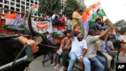 Congress party supporters shout slogans as they ride on bullock carts during a protest against fuel price hike and other economy issues in Bangalore, India, Sept. 10, 2018.