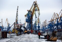 FILE - Workers pass in Mariupol trade port in Mariupol, eastern Ukraine, Dec. 2, 2018.