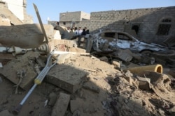 People stand at the site of a Houthi ballistic missile attack over the populated district of Rawda in Marib, Yemen, Feb. 6, 2020.