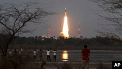 People watch as Indian Space Research Organization’s Geosynchronous Satellite Launch Vehicle Mk III rocket lifts off from the space launch center in Sriharikota, India, June 5, 2017.