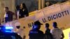 FILE - A migrant disembarks escorted by police from Italy's Diciotti coast guard vessel carrying 67 asylum seekers berthed at Trapani port on July 12, 2018. 
