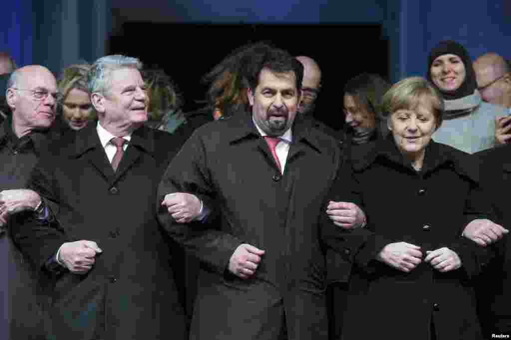 Presiden Bundestag atau Parlemen Jerman, Norbert Lammert, Presiden Jerman Joachim Gauck, Ketua Dewan Pusat Muslim di Jerman Aiman Mazyek dan Kanselir Jerman Angela Merkel, bergandengan tangan dalam doa bersama yang diorganisir kelompok-kelompok Muslim untuk para korban penembakan teror oleh pria-pria bersenjata di kantor Charlie Hebdo, di depan Gerbang Brandenburg di Berlin (13/1). (Reuters/Maurizio Gambarini)