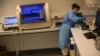 FILE - A woman works with collected samples for a COVID-19 PCR test a hospital in Liege, Belgium, May 8, 2020. 